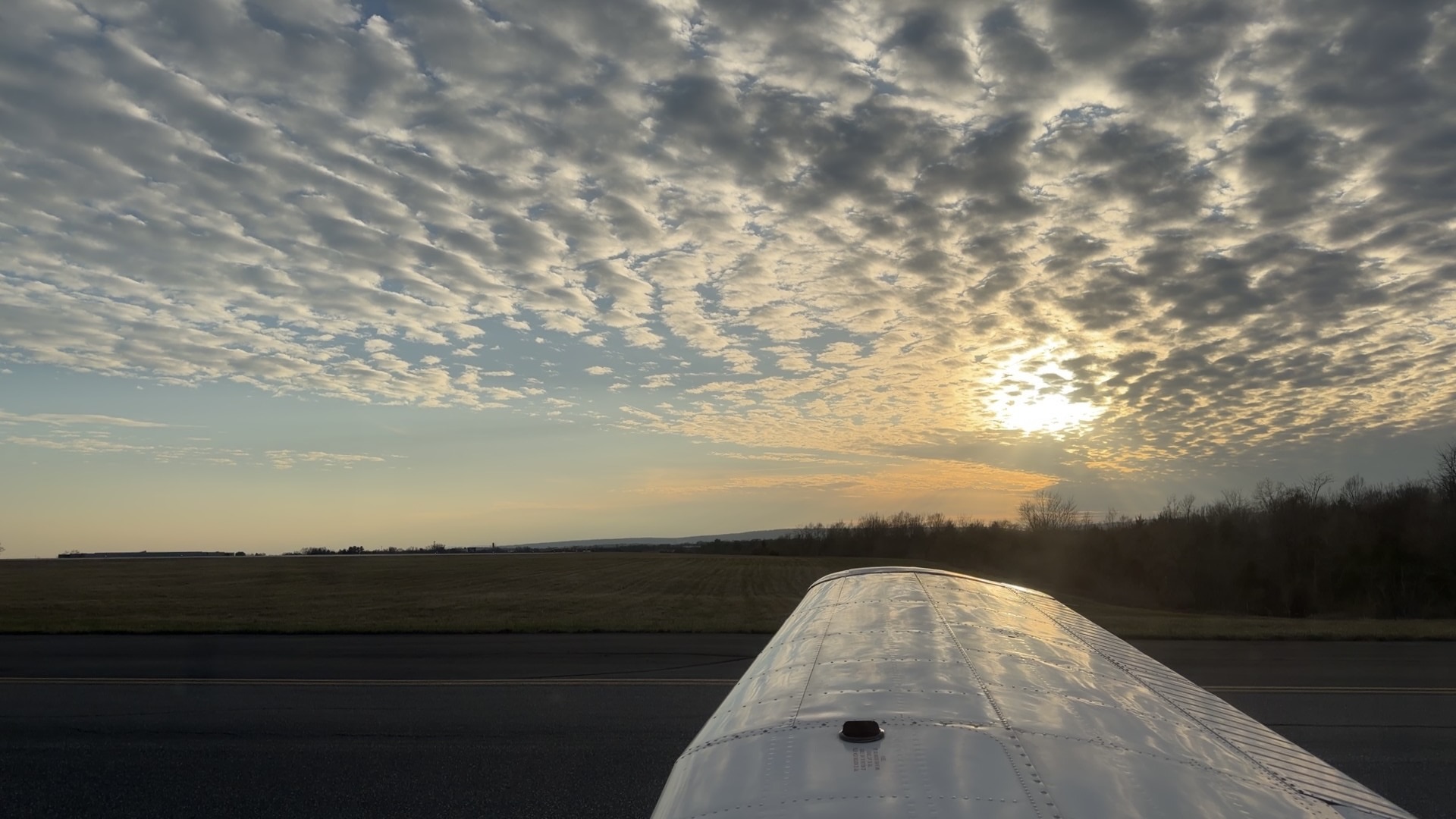 Wing view of clouds over the runway at sunset